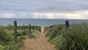 Un sendero arenoso que lleva al mar, flanqueado por postes de madera.