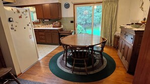 Uma cozinha com mesa de jantar, armários de madeira, geladeira e ventilador de teto.