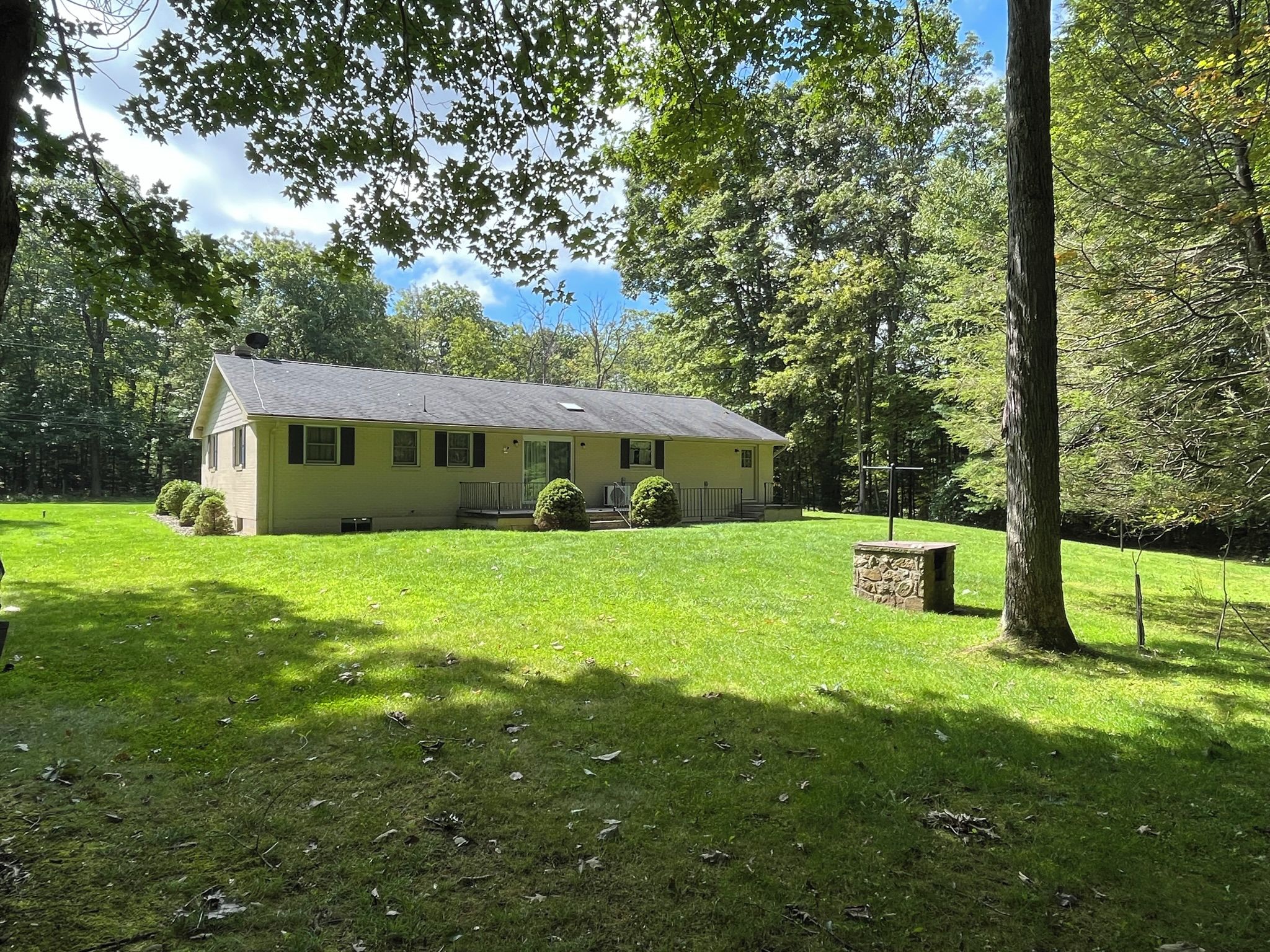 A single-story house with a sloped roof, surrounded by a well-maintained lawn and trees.