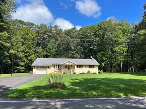 A two-story house with a front porch, a garage, and a well-maintained lawn.