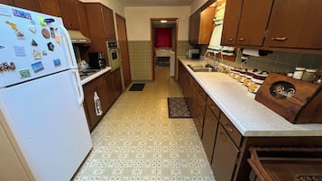 A kitchen with wooden cabinets, a white refrigerator, and a patterned floor.