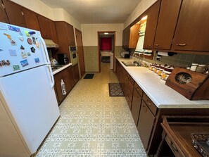 Una cocina con armarios de madera, un refrigerador blanco y un piso con diseño.
