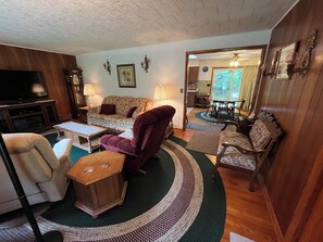 A living room with a sofa, armchairs, a coffee table, and a television.