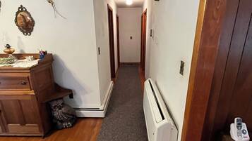 Un couloir avec un plancher en bois, un radiateur et une porte sur le côté droit.