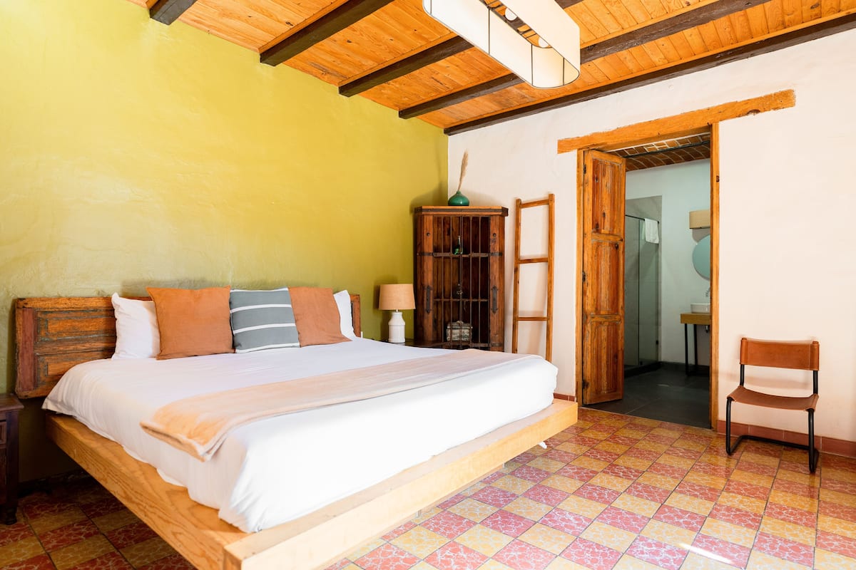 A bedroom with a wooden bed, a nightstand, a wooden cabinet, and a chair.