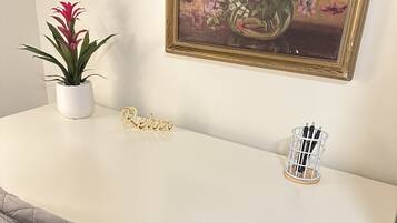 Et hvidt skrivebord med en potteplante, et indrammet billede og et navneskilt.