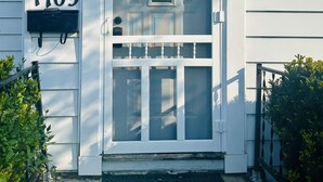 Une maison blanche avec le numéro 1709 sur la porte, un petit porche et un paillasson noir.