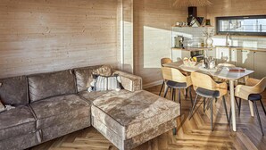 A cozy living area with a brown leather sofa, a dining table with chairs, and a kitchen area with a window. - 2 bedroom cozy home in Trzesacz (Trzesacz)