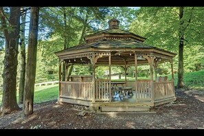 Situated in a serene wooded area, this hexagonal gazebo offers a peaceful space for relaxation or dining.