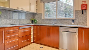 Una cocina moderna con armarios de madera, lavavajillas de acero inoxidable y una ventana con vistas al exterior.