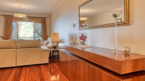 Una sala de estar moderna con un sofá, un aparador de madera, un espejo grande y una lámpara de pie.