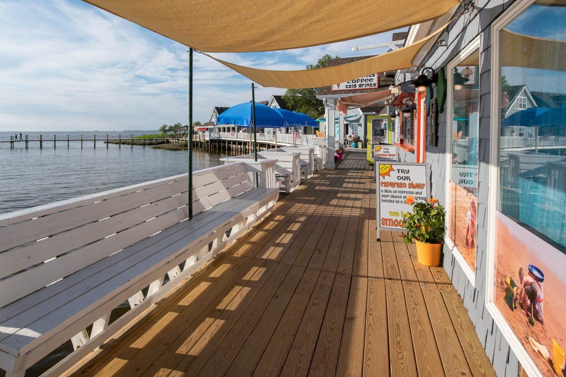 A wooden deck with a canopy, a coffee shop, and a view of the water.