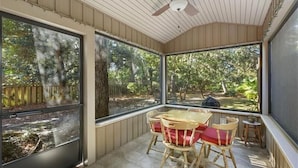 A covered patio with a table and chairs, large windows, and a ceiling fan. - All Wright : 2 BR, 1 BA Duplex in Jekyll Island, Sleeps 4 (Jekyll Island)