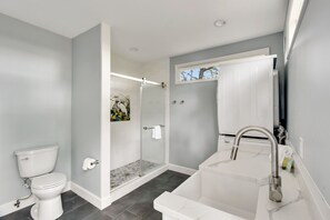 A modern bathroom with a toilet, shower, and sink.