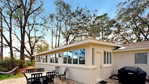 Eine Terrasse mit Pflasterboden, einem Tisch mit Stühlen und einem Grill.