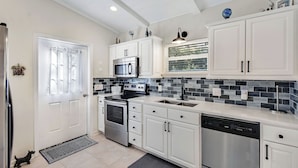 A modern kitchen with white cabinets, stainless steel appliances, and a tiled backsplash.