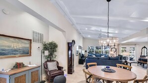 A spacious living area with a dining table, sofas, and a chandelier.