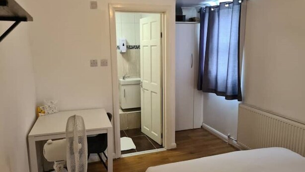 Una habitación pequeña y funcional con cama, escritorio, silla y armario.