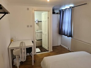 A small, compact room with a bed, a desk with a chair, and a wardrobe. - A fabulous 4-bedroom house with 2parking space. (London)