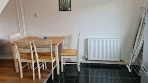 Un comedor con una mesa y sillas de madera, un radiador y un cuadro en la pared.