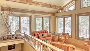 A spacious living area with large windows, a wooden ceiling, and a cozy seating arrangement. - Charming 3-bedroom chalet right off the ski slopes! (Lead)