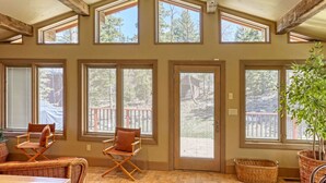 A room with large windows, wicker furniture, and a view of a deck. - Charming 3-bedroom chalet right off the ski slopes! (Lead)