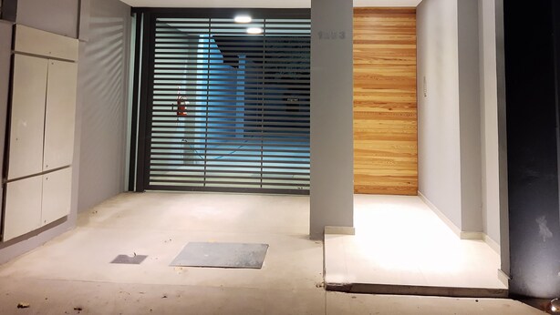 A modern interior with a wooden panel wall, a metal gate, and a concrete floor. - Drummond Apartments (Luján de Cuyo)