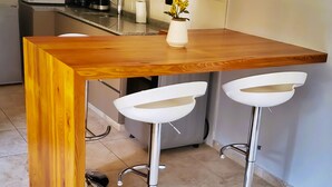 A kitchen with a wooden bar counter, a microwave, and a coffee maker. - Drummond Apartments (Luján de Cuyo)
