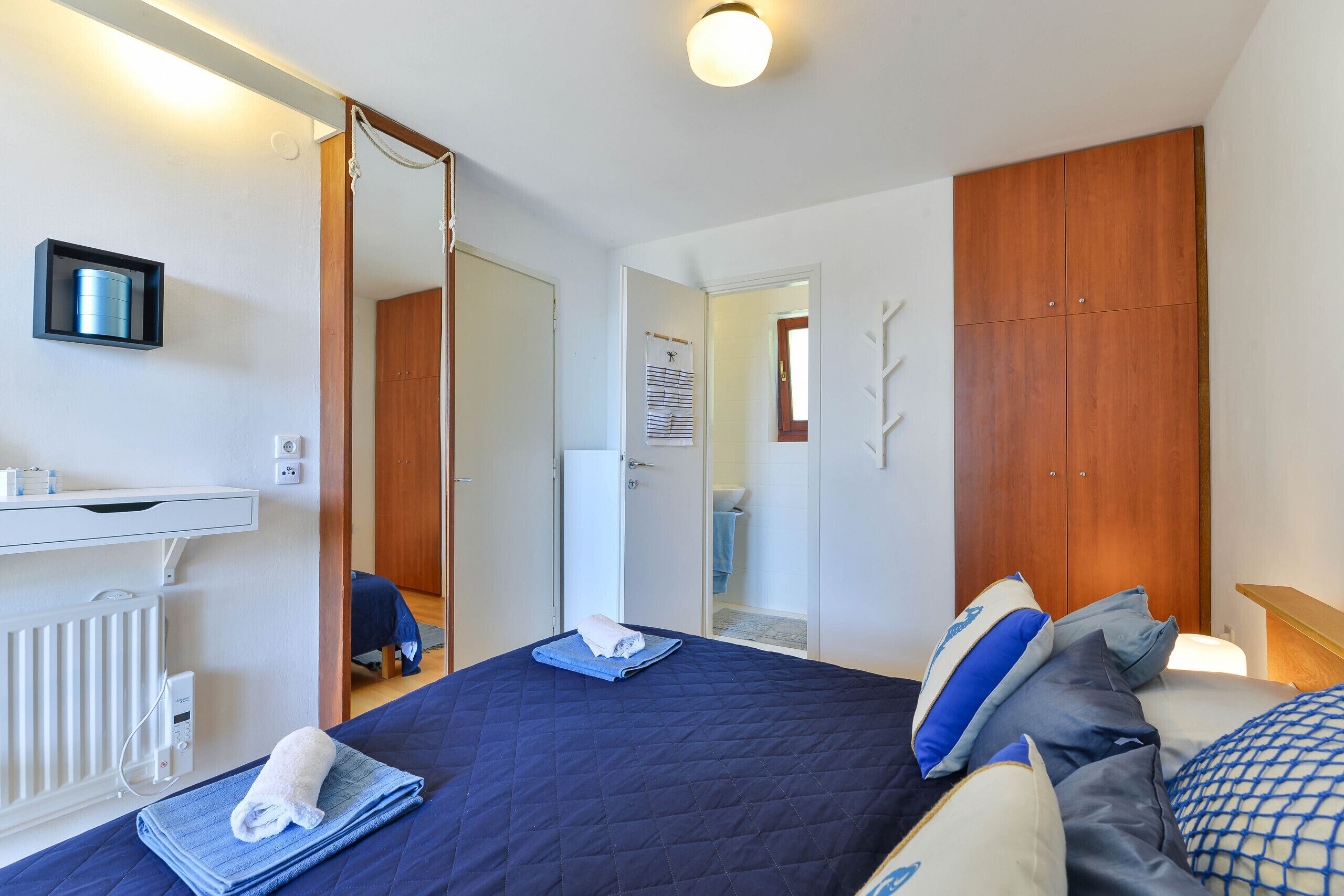 Ein Schlafzimmer mit einem Bett, einem Nachttisch, einem Spiegel, einem Kleiderschrank und einer Heizung.