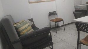 A small, clean room with a white table, two chairs, a window, and a tiled floor. - Ginjals-67 (Almargem do Bispo)