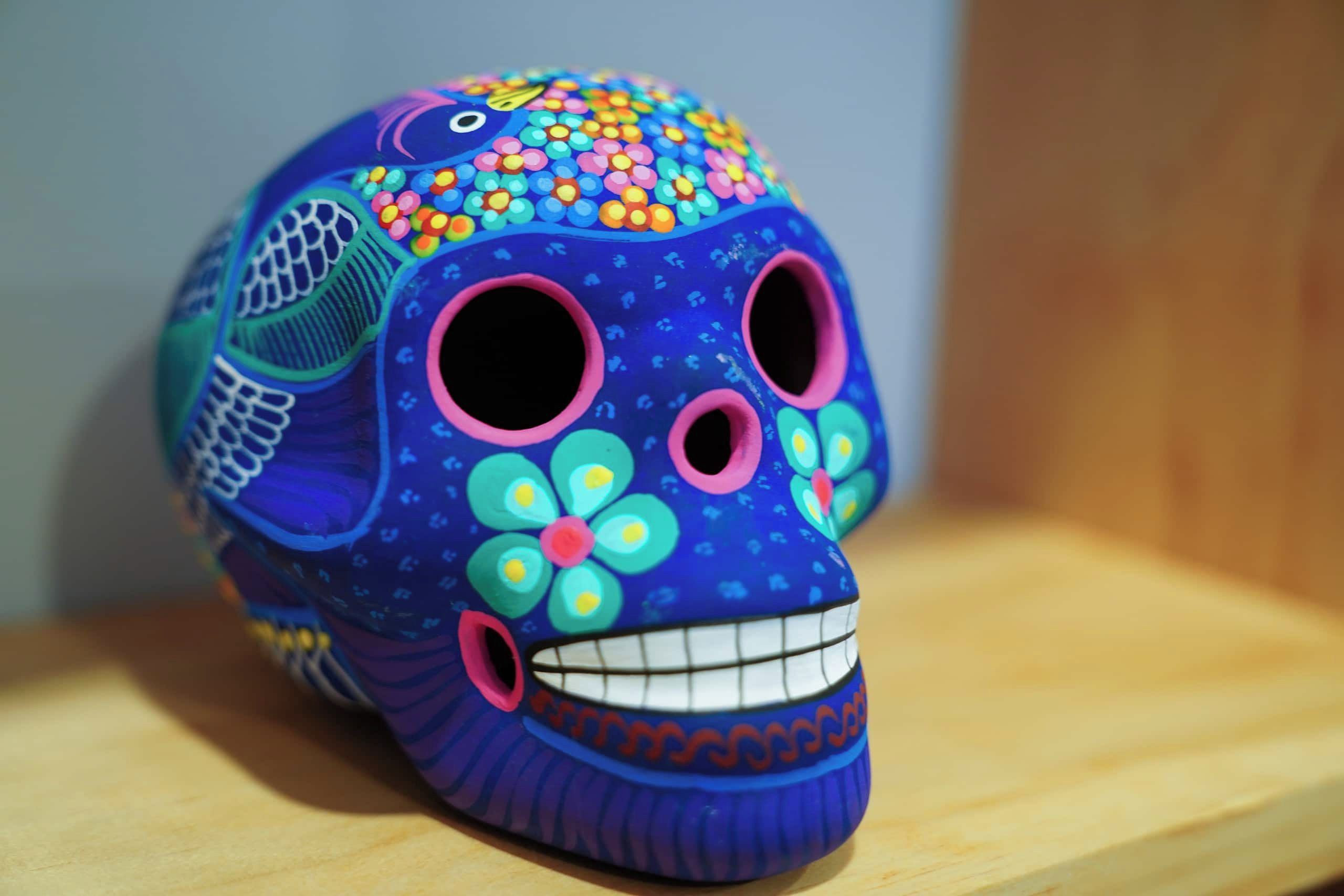 A colorful skull sculpture with floral patterns and a smiling face.