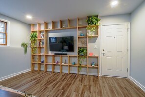 Een kamer met een houten entertainmentkast, een flatscreen televisie en een witte deur.