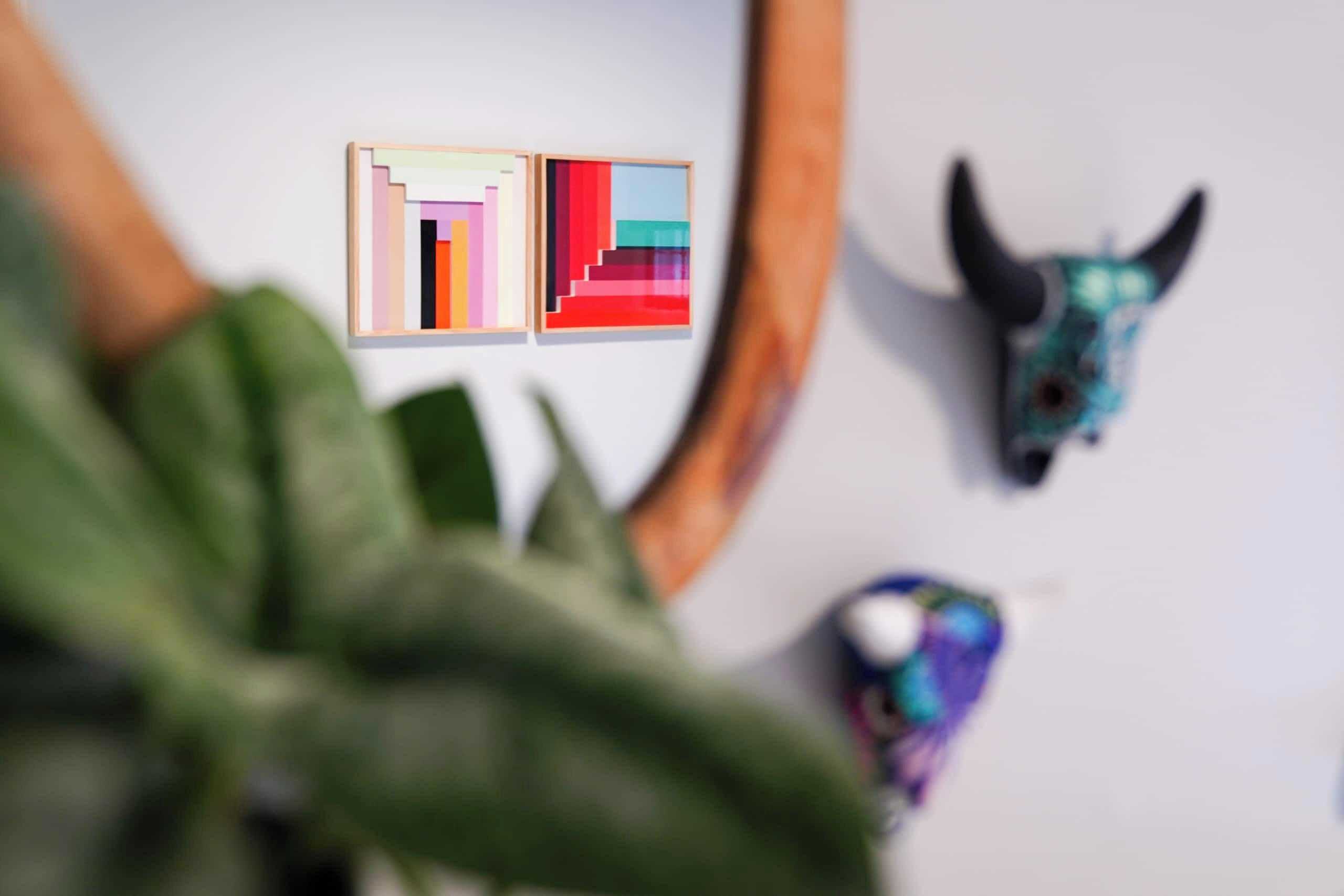 A wall with two framed pixel art pieces and a skull decoration.