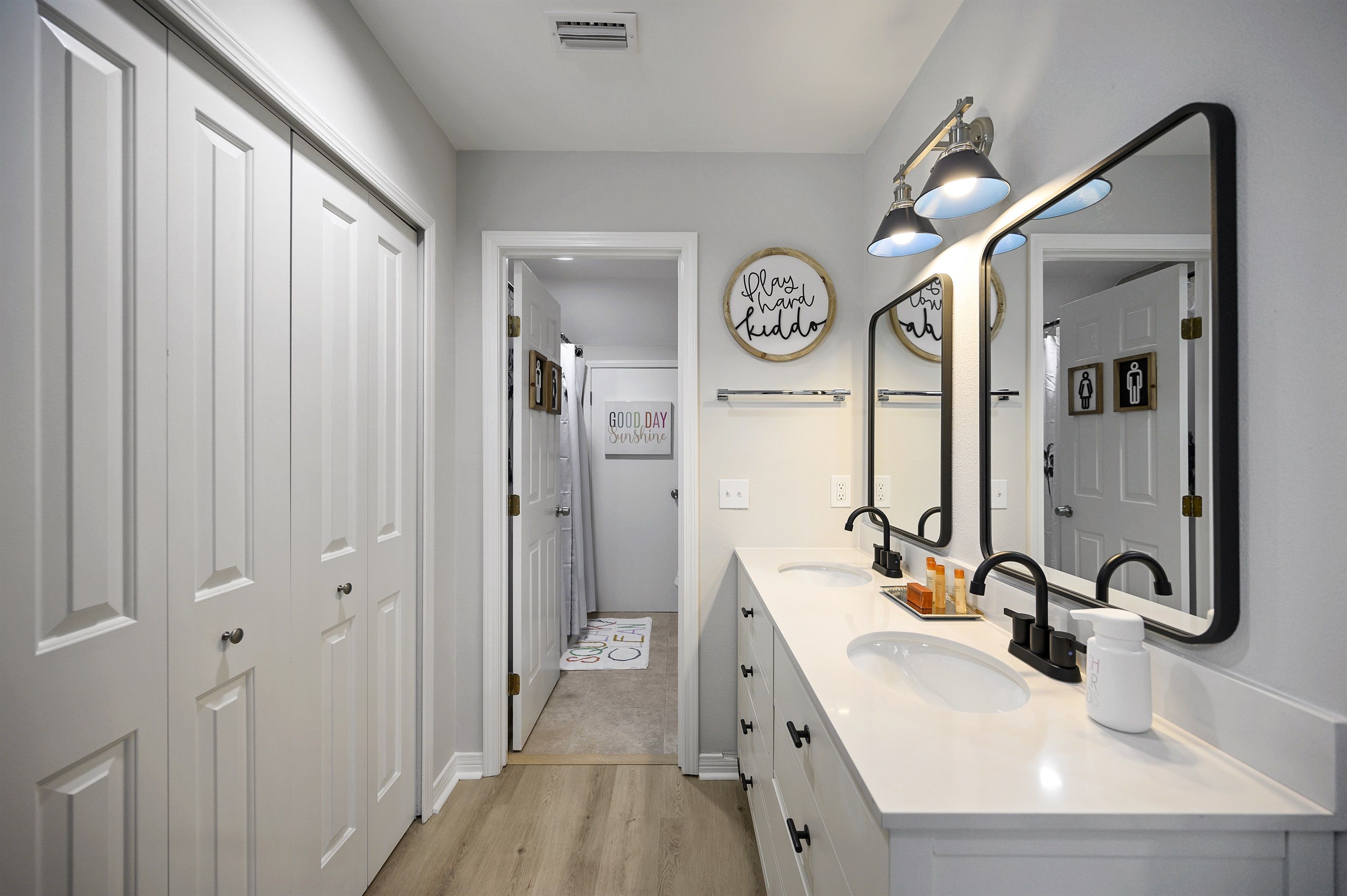 A modern bathroom with a double sink vanity, a large mirror, and a shower area.