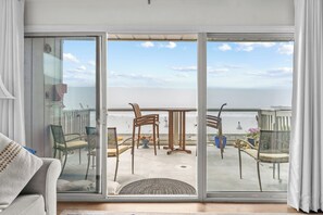 A balcony with a view of the sea, furnished with chairs and a table.