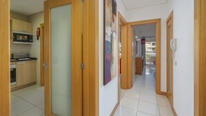 En hall med trädörrar, ett köksområde med mikrovågsugn och ett klinkergolv.