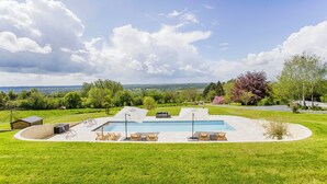 Una piscina con sillas de descanso, zona de barbacoa y vistas al campo.