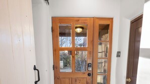 A wooden door with glass panels, a metal handle, and a keyhole. - Mariposa | Charming Adobe Home in Santa Fe (Santa Fe)
