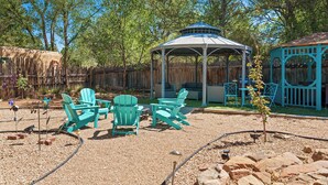 A gazebo with a curved roof, surrounded by a wooden fence, and outdoor seating with chairs and a table. - Mariposa | Charming Adobe Home in Santa Fe (Santa Fe)