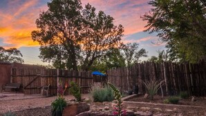 A garden with a wooden fence, a bench, and a blue tarp.