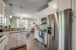 A modern kitchen with white cabinetry, stainless steel appliances, and a granite countertop.