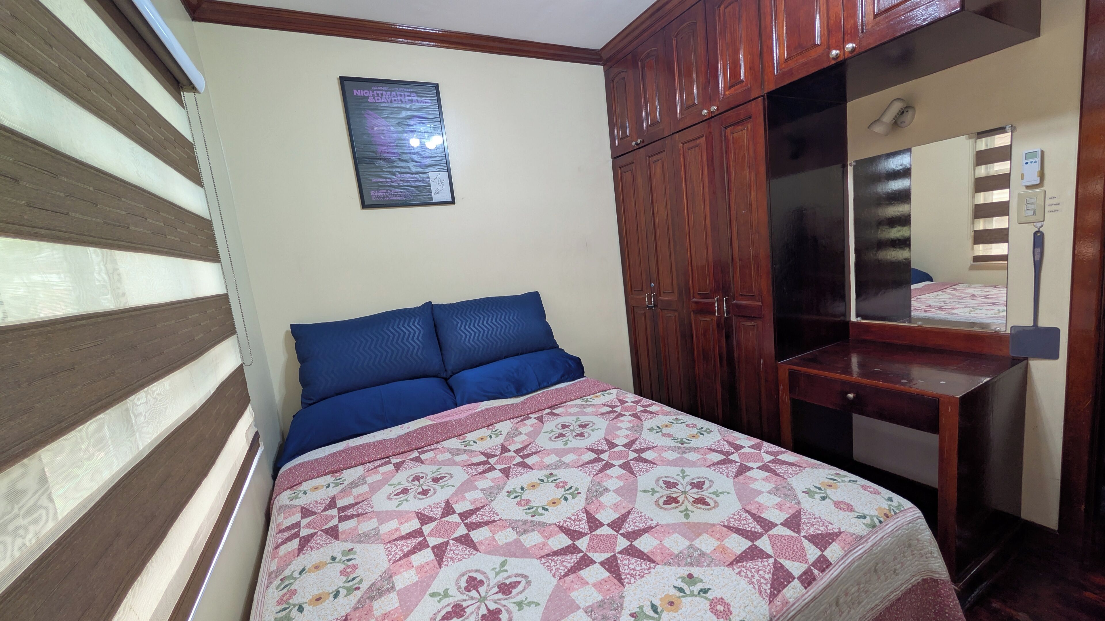A bedroom with a bed, a dresser, a mirror, and a poster on the wall.
