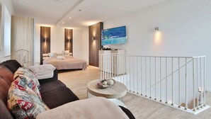 Een moderne woonkamer met een bank, een salontafel en een bed, met een televisie aan de muur.