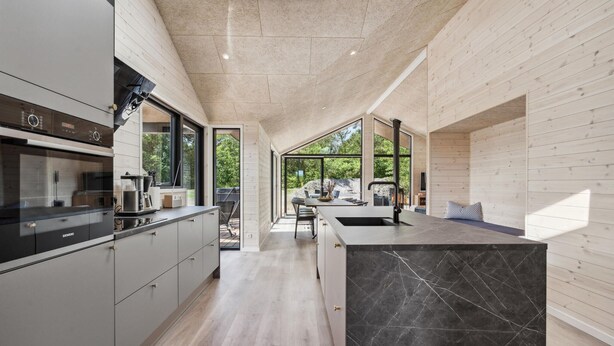A modern kitchen with a large island, built-in appliances, and a view to an outdoor dining area. - Nice home in Tarm with WiFi (Tarm)