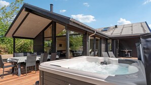 A hot tub on a wooden deck with outdoor furniture, a covered patio area, and a building with large windows. - Nice home in Tarm with WiFi (Tarm)