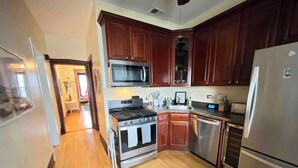 A kitchen with wooden cabinets, stainless steel appliances, and a wooden floor. - Irving Park/Avondale Updated Vintage Top Unit in 2-Flat (Chicago)