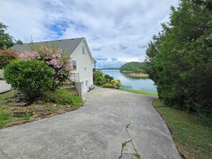 A house with a driveway leading to a lake, surrounded by greenery and a clear sky. - 20% OFF Dock, Dock, Lakefront, Angel Cove Hideaway (Dandridge)