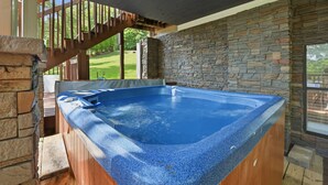 A hot tub with a stone wall and wooden deck, a staircase, and a view of a green landscape. - 20% OFF NEW Dock, Pavilion, Hot Tub, Kayaks, Lakefront- Blue Heron Landing (Dandridge)