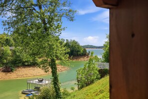 Blick auf einen Fluss mit einem Steg, Bäumen und blauem Himmel.