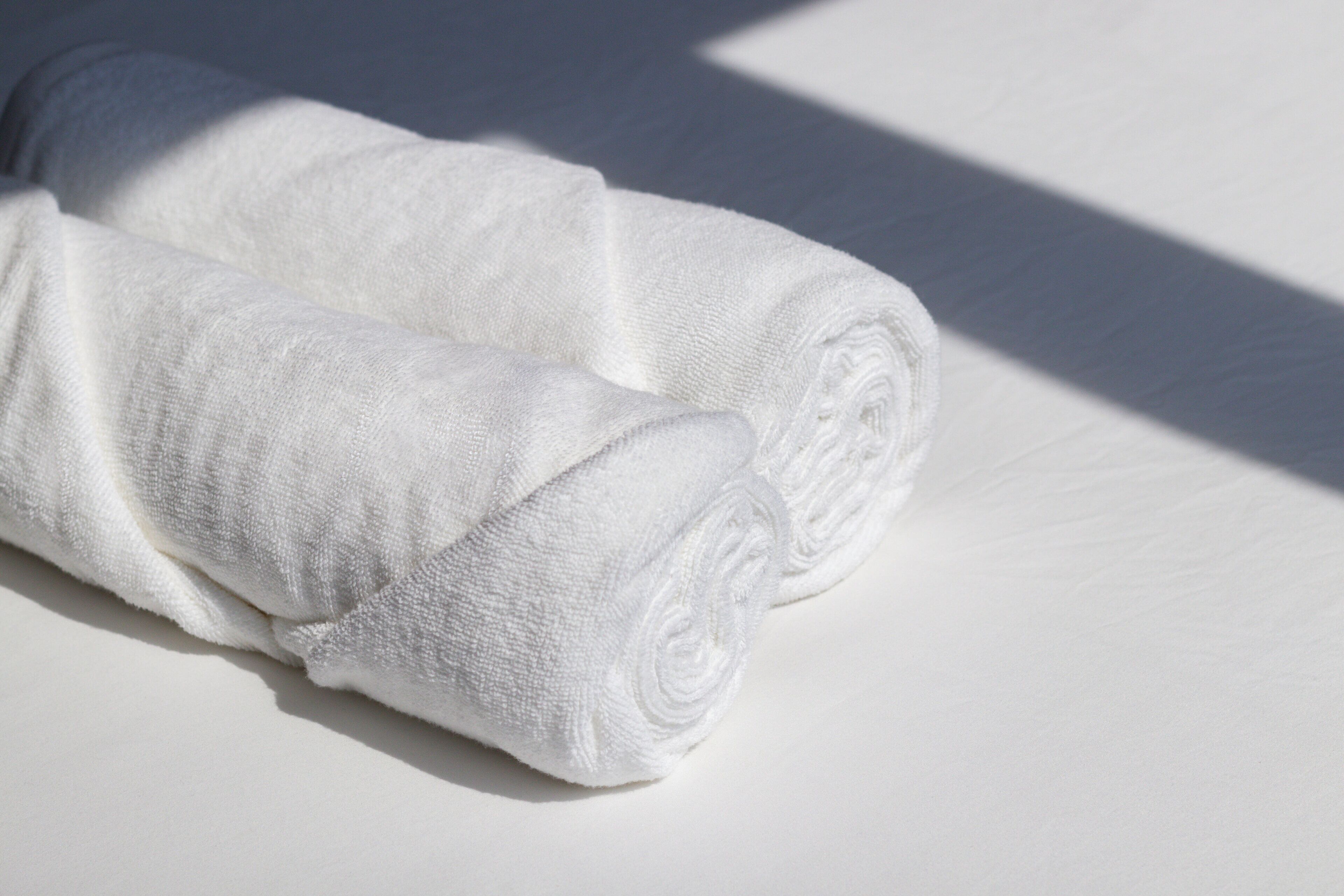 Two rolled white towels on a white surface.